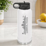 White 32 oz insulated water bottle laser engraved with the Lubbock, Texas skyline running up the side, standing on a kitchen counter