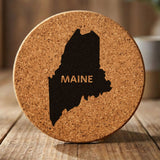 Maine round cork coaster engraved with the state shape and MAINE in bold lettering