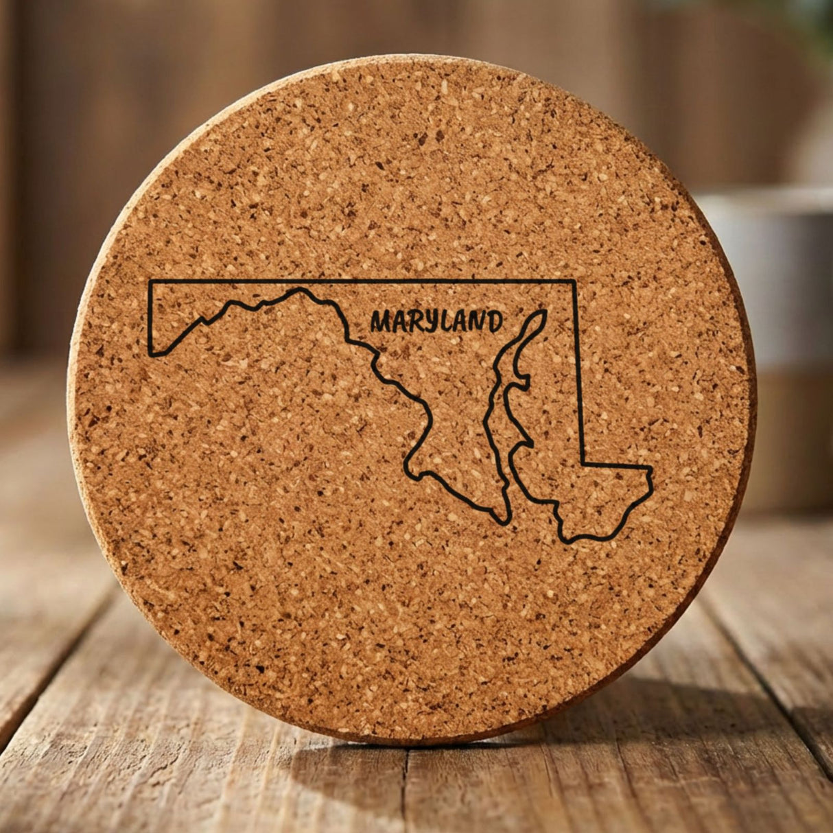 Maryland round cork coaster engraved with the state outline and MARYLAND in hand-drawn brush lettering