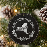 Black leatherette round Christmas ornament engraved Merry Christmas From New York, with the state shape in a laurel wreath, hanging on a tree