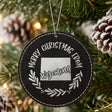 Black leatherette round Christmas ornament engraved Merry Christmas From Wyoming, with the state shape in a laurel wreath, hanging on a tree