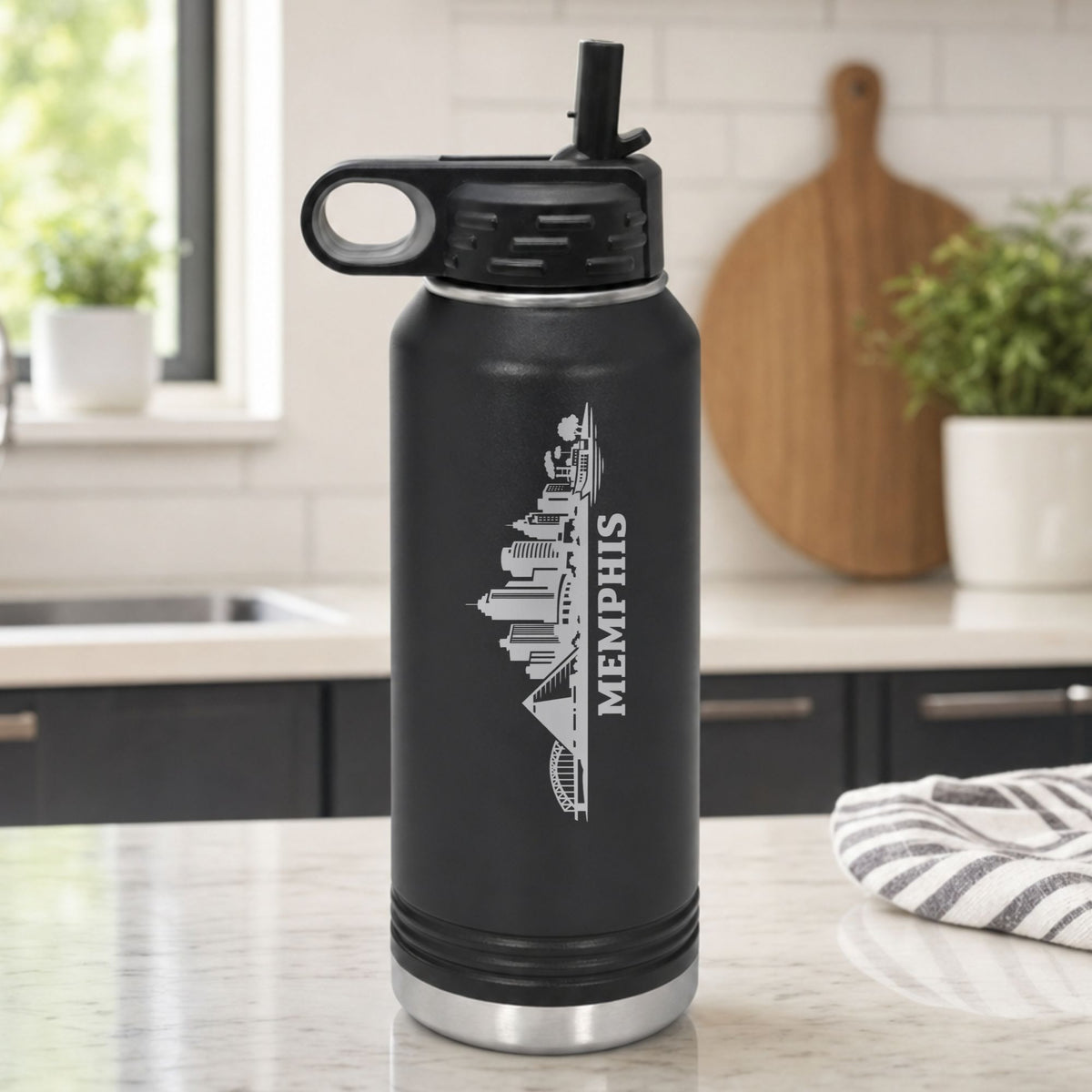 Black 32 oz insulated water bottle laser engraved with the Memphis, Tennessee skyline running up the side, standing on a kitchen counter