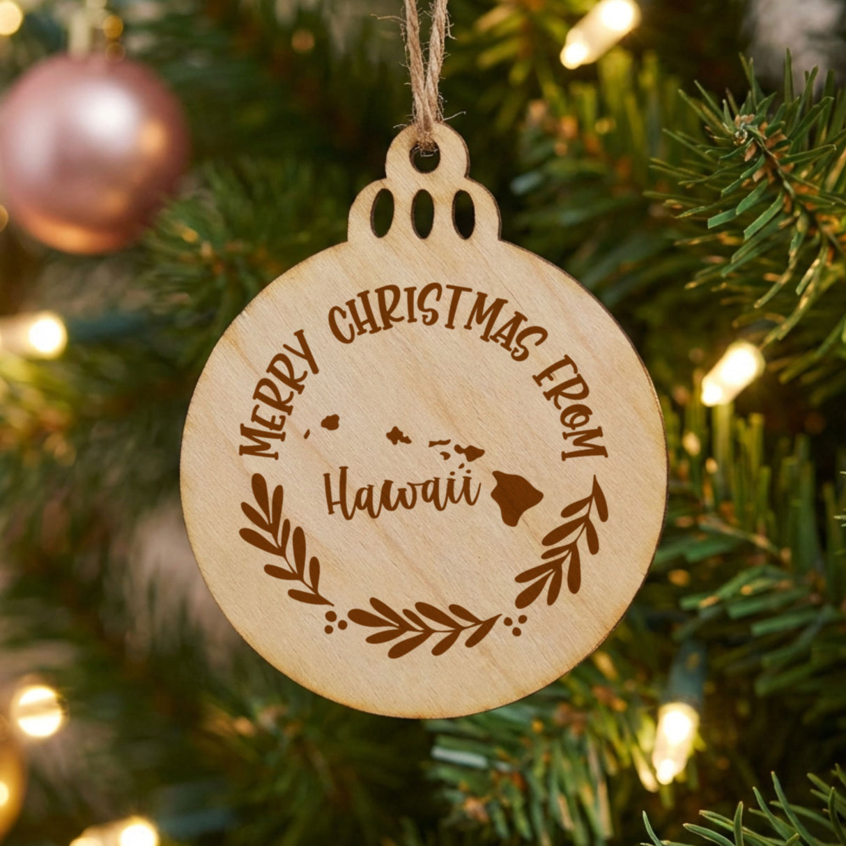 Round wood Christmas ornament engraved Merry Christmas From Hawaii, with the state shape in a laurel wreath
