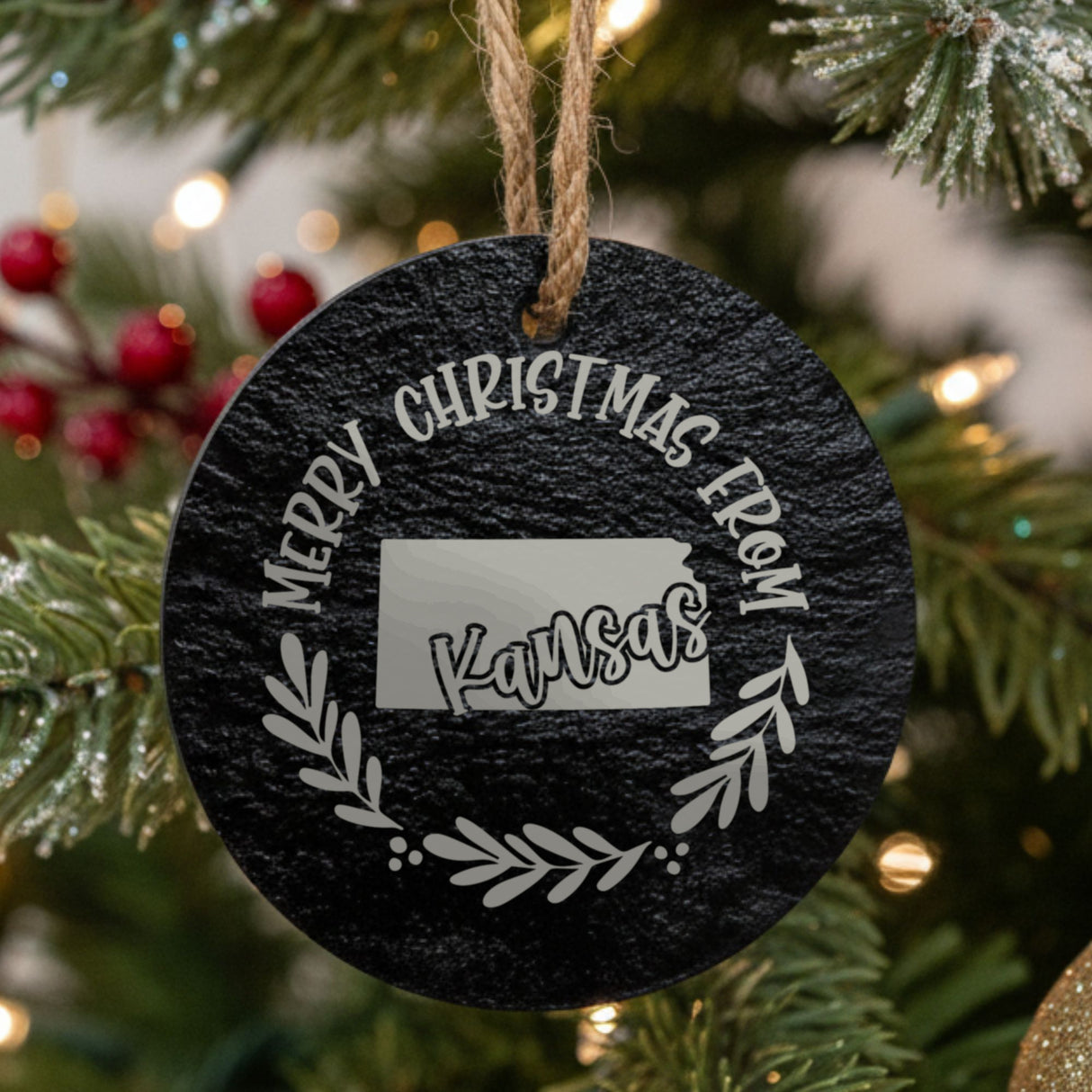 Round slate Christmas ornament engraved Merry Christmas From Kansas, with the state shape in a laurel wreath