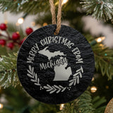 Round slate Christmas ornament engraved Merry Christmas From Michigan, with the state shape in a laurel wreath