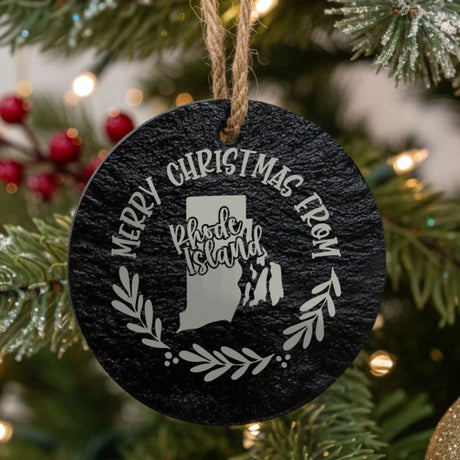 Round slate Christmas ornament engraved Merry Christmas From Rhode Island, with the state shape in a laurel wreath