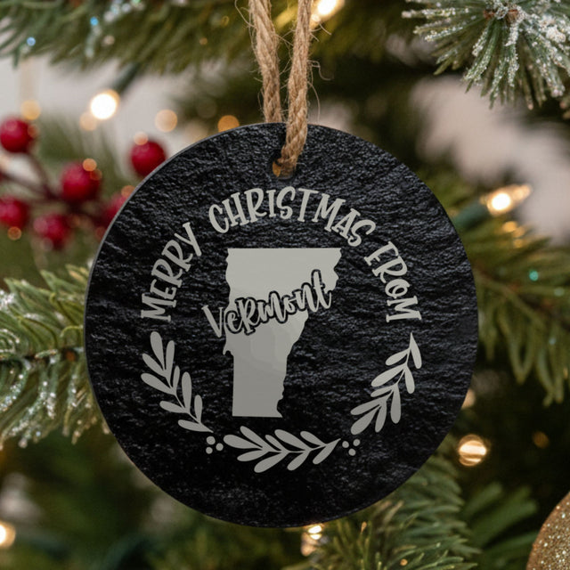 Round slate Christmas ornament engraved Merry Christmas From Vermont, with the state shape in a laurel wreath
