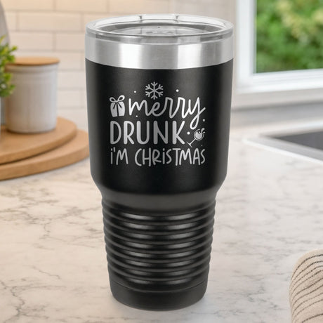 Black 30 oz tumbler laser engraved with "Merry Drunk, I'm Christmas", on a kitchen counter