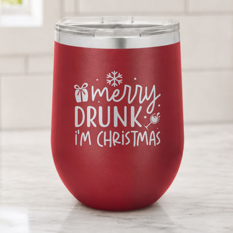 Maroon 12 oz stemless wine tumbler laser engraved with "Merry Drunk, I'm Christmas", on a kitchen counter