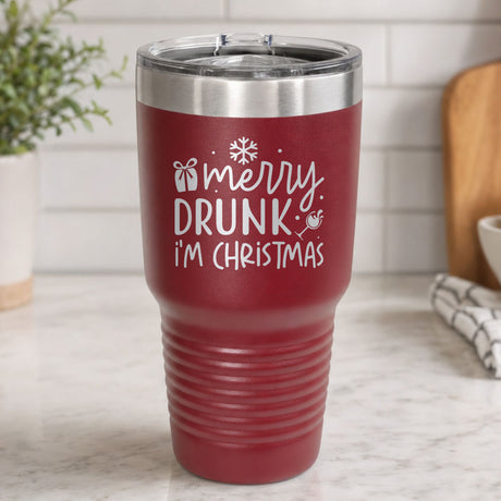Maroon 30 oz tumbler laser engraved with "Merry Drunk, I'm Christmas", on a kitchen counter