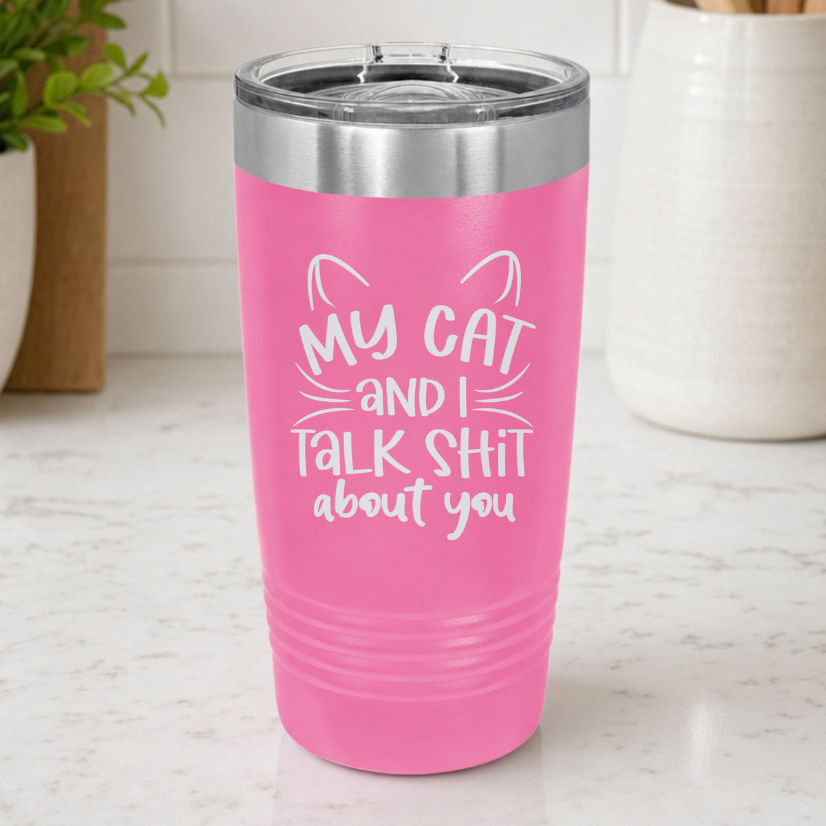 Pink 20 oz tumbler laser engraved with "My Cat and I Talk Sh*t About You", plus cat ears and whiskers, on a kitchen counter