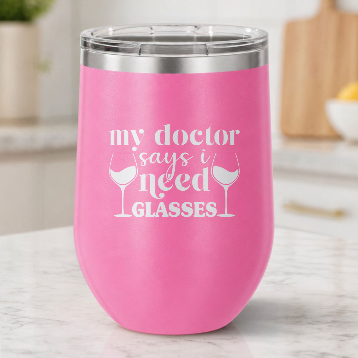 Pink 12 oz stemless wine tumbler laser engraved with "My Doctor Says I Need Glasses", on a kitchen counter