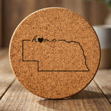 Nebraska round cork coaster engraved with the state outline and home in script with a heart