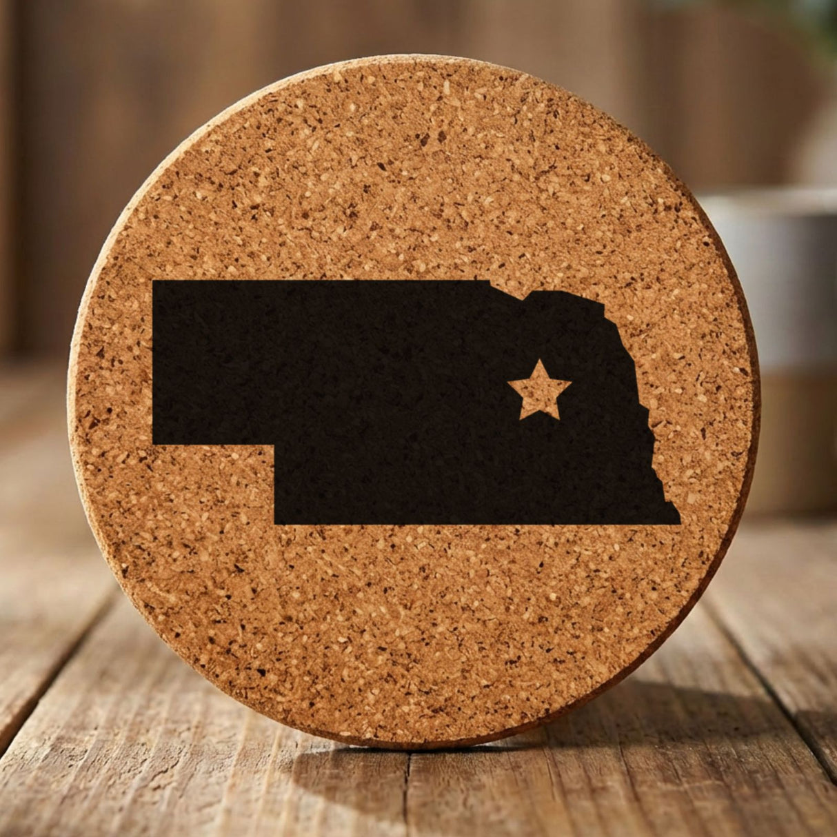 Nebraska round cork coaster engraved with the state shape and a star