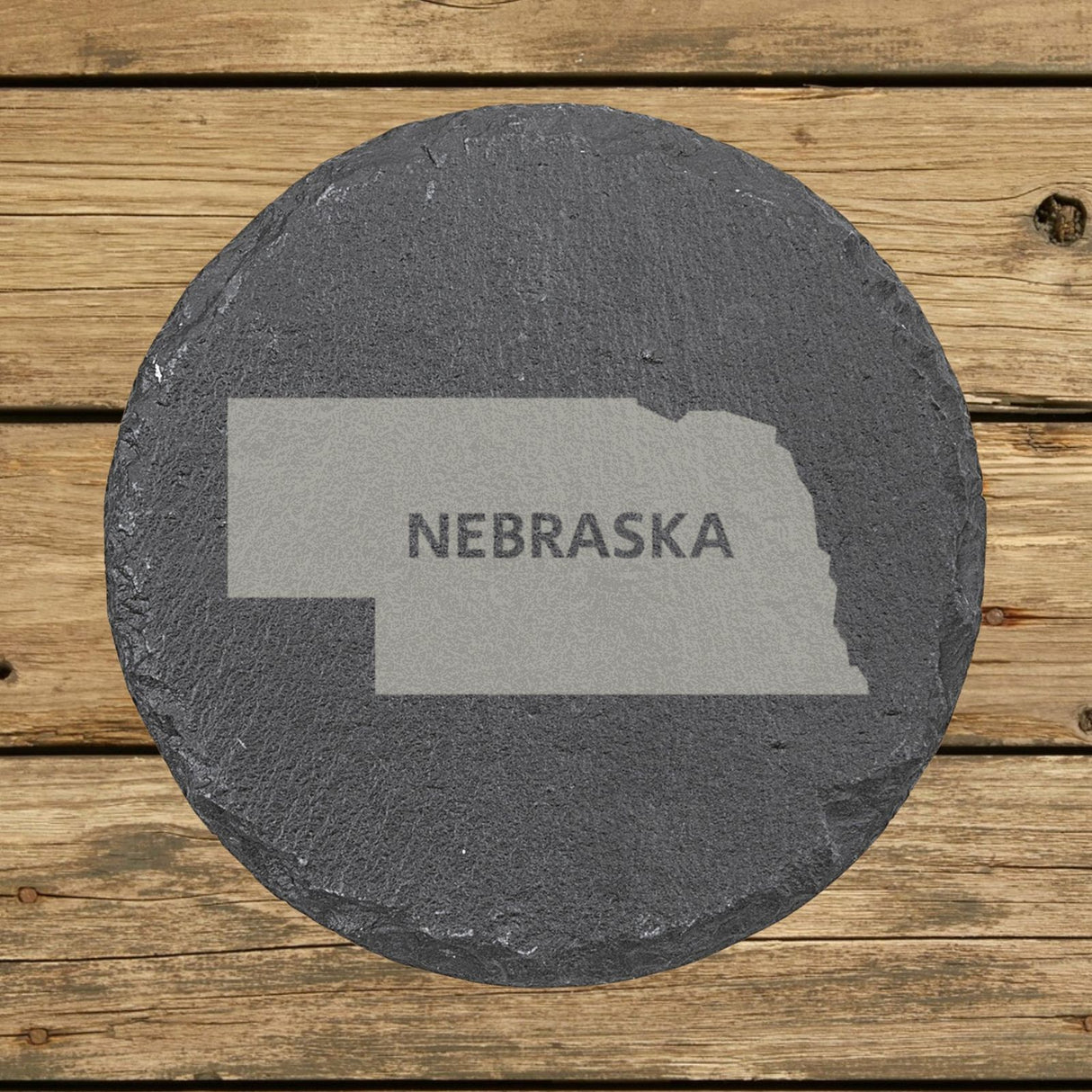 Nebraska round slate coaster engraved with the state shape and NEBRASKA in bold lettering