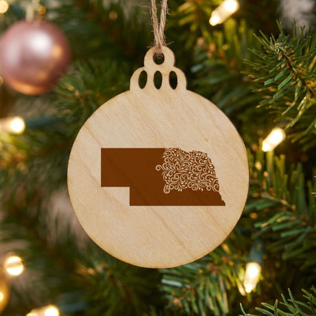 Nebraska round wood Christmas ornament engraved with the state shape in ornate floral scrollwork
