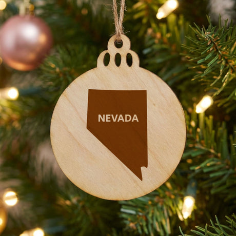 Nevada round wood Christmas ornament engraved with the state shape and NEVADA in bold lettering