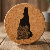 New Hampshire round cork coaster engraved with the state shape in ornate floral scrollwork