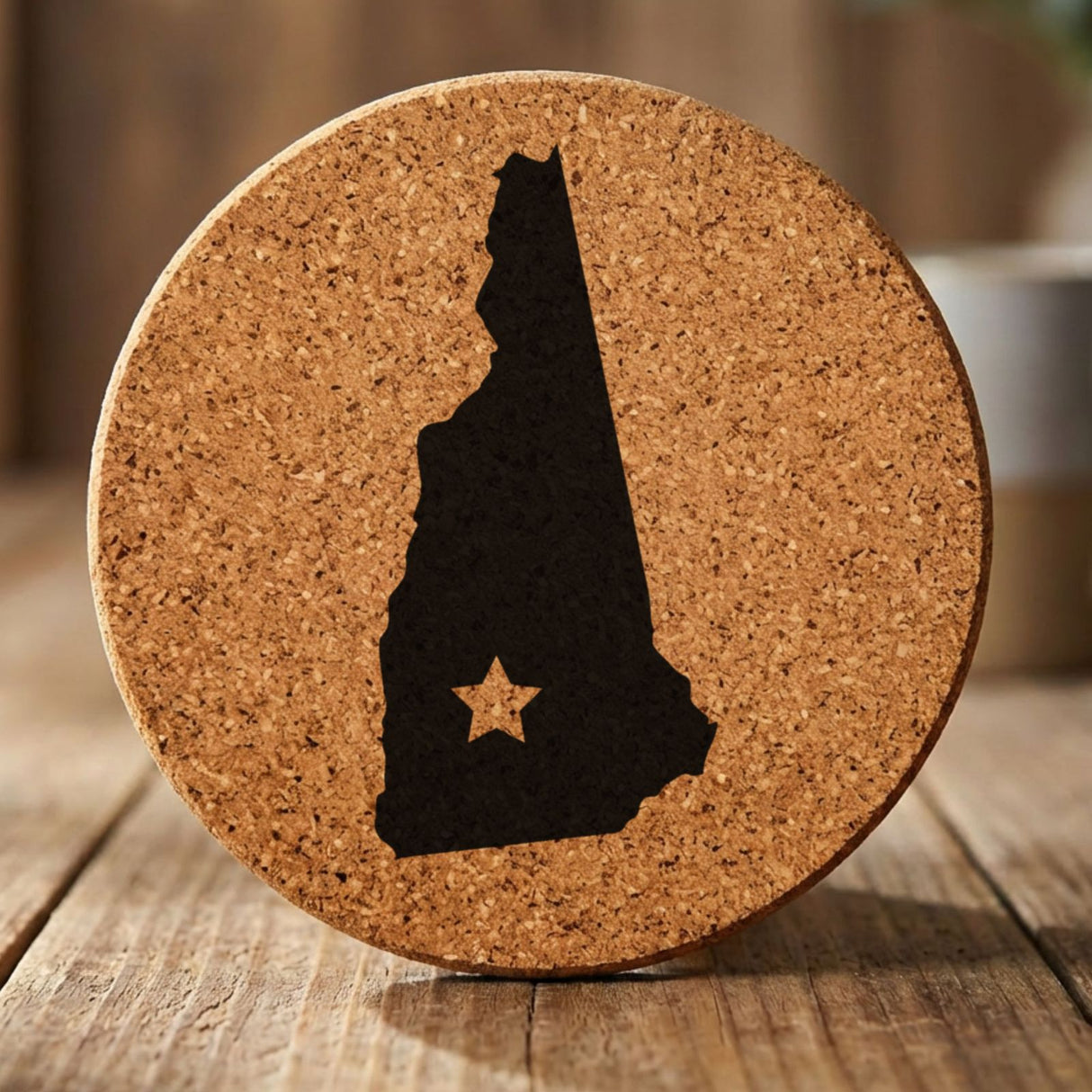 New Hampshire round cork coaster engraved with the state shape and a star