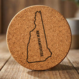 New Hampshire round cork coaster engraved with the state outline and NEW HAMPSHIRE running vertically