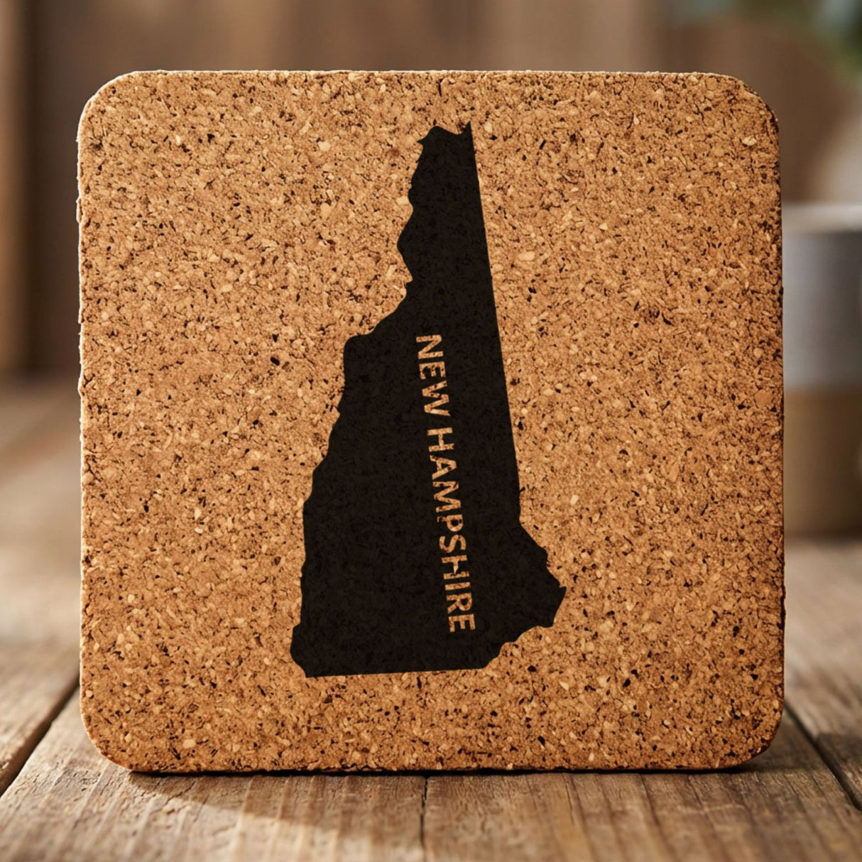 New Hampshire square cork coaster with the engraved state shape and NEW HAMPSHIRE running vertically