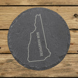 New Hampshire round slate coaster engraved with the state outline and NEW HAMPSHIRE running vertically