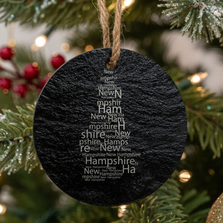 New Hampshire round slate Christmas ornament engraved with a word cloud of repeating New Hampshire text