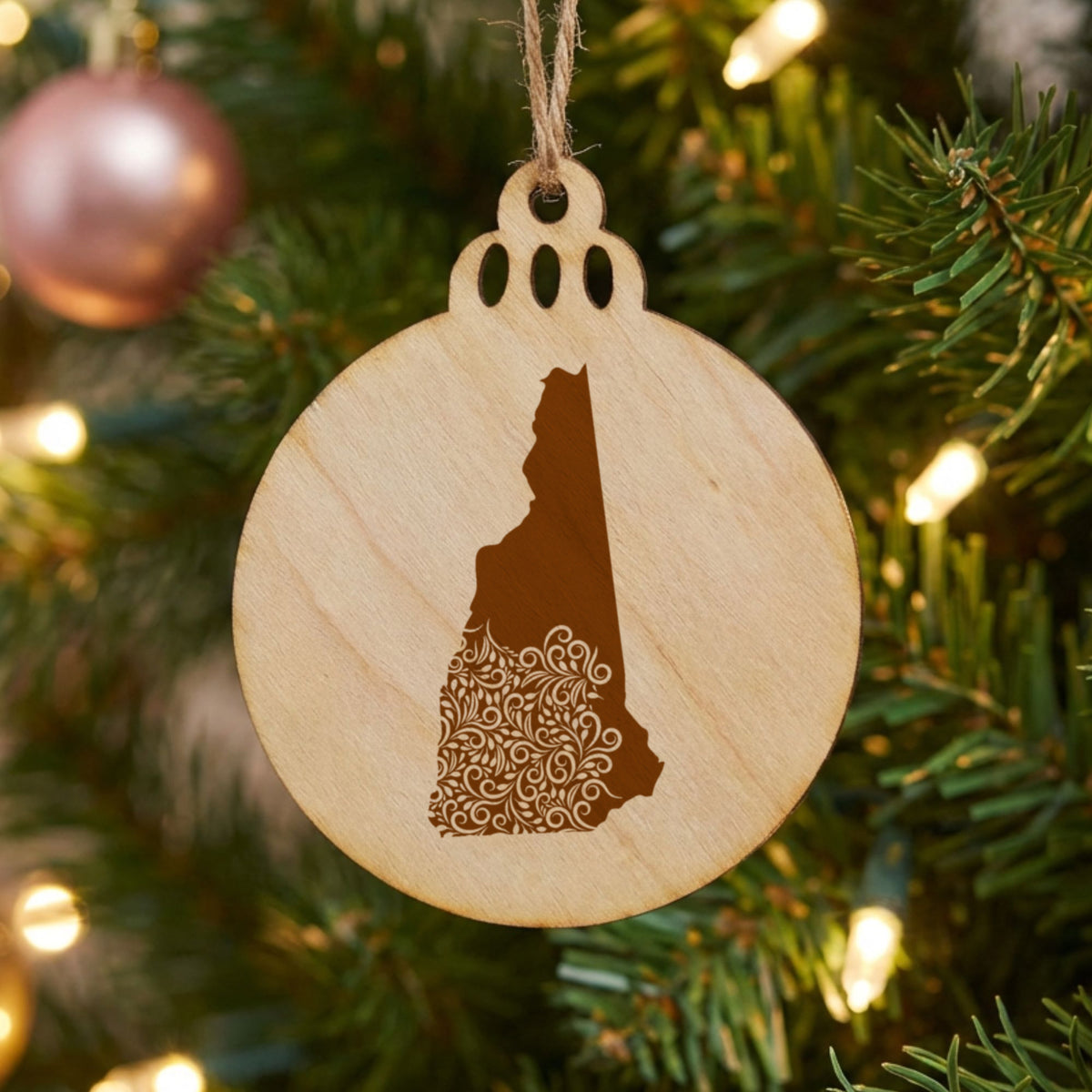 New Hampshire round wood Christmas ornament engraved with the state shape in ornate floral scrollwork