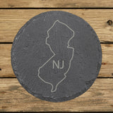 New Jersey round slate coaster engraved with the state outline and NJ initials