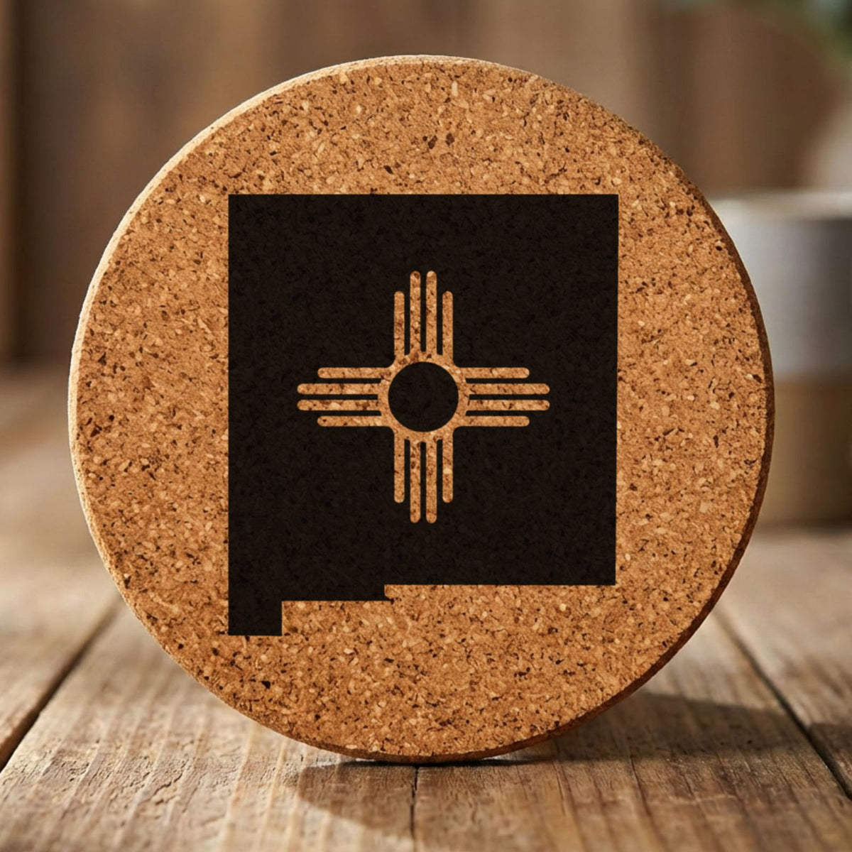 New Mexico round cork coaster engraved with the state shape and the Zia sun symbol