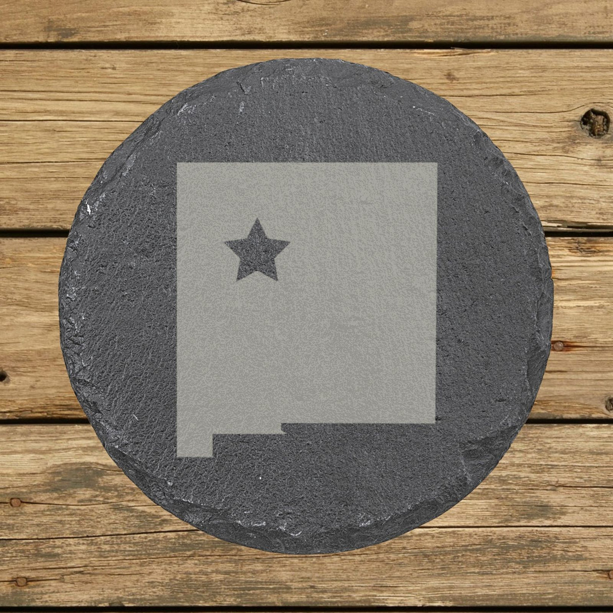 New Mexico round slate coaster engraved with the state shape and a star