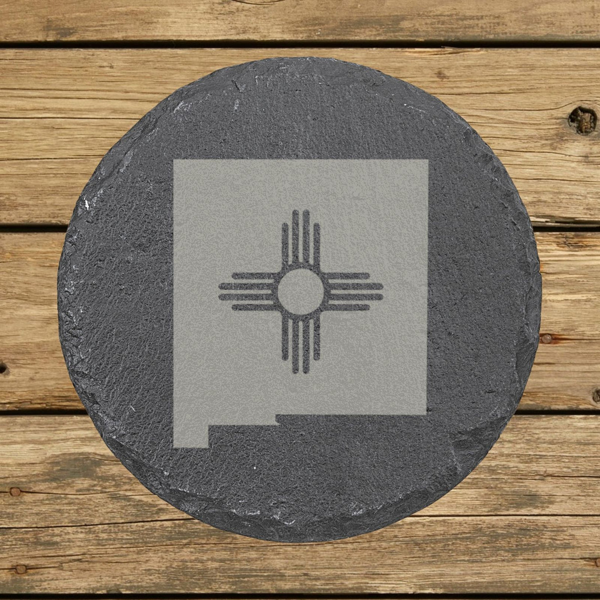 New Mexico round slate coaster engraved with the state shape and the Zia sun symbol