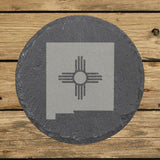 New Mexico round slate coaster engraved with the state shape and the Zia sun symbol