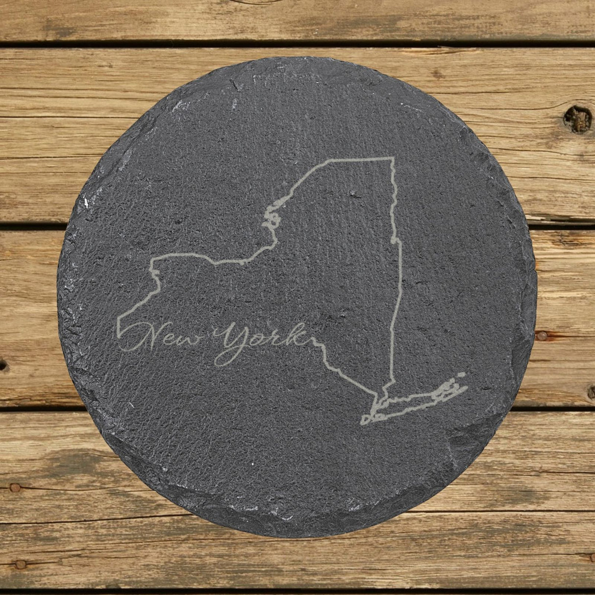 New York round slate coaster engraved with the state outline and New York in script lettering