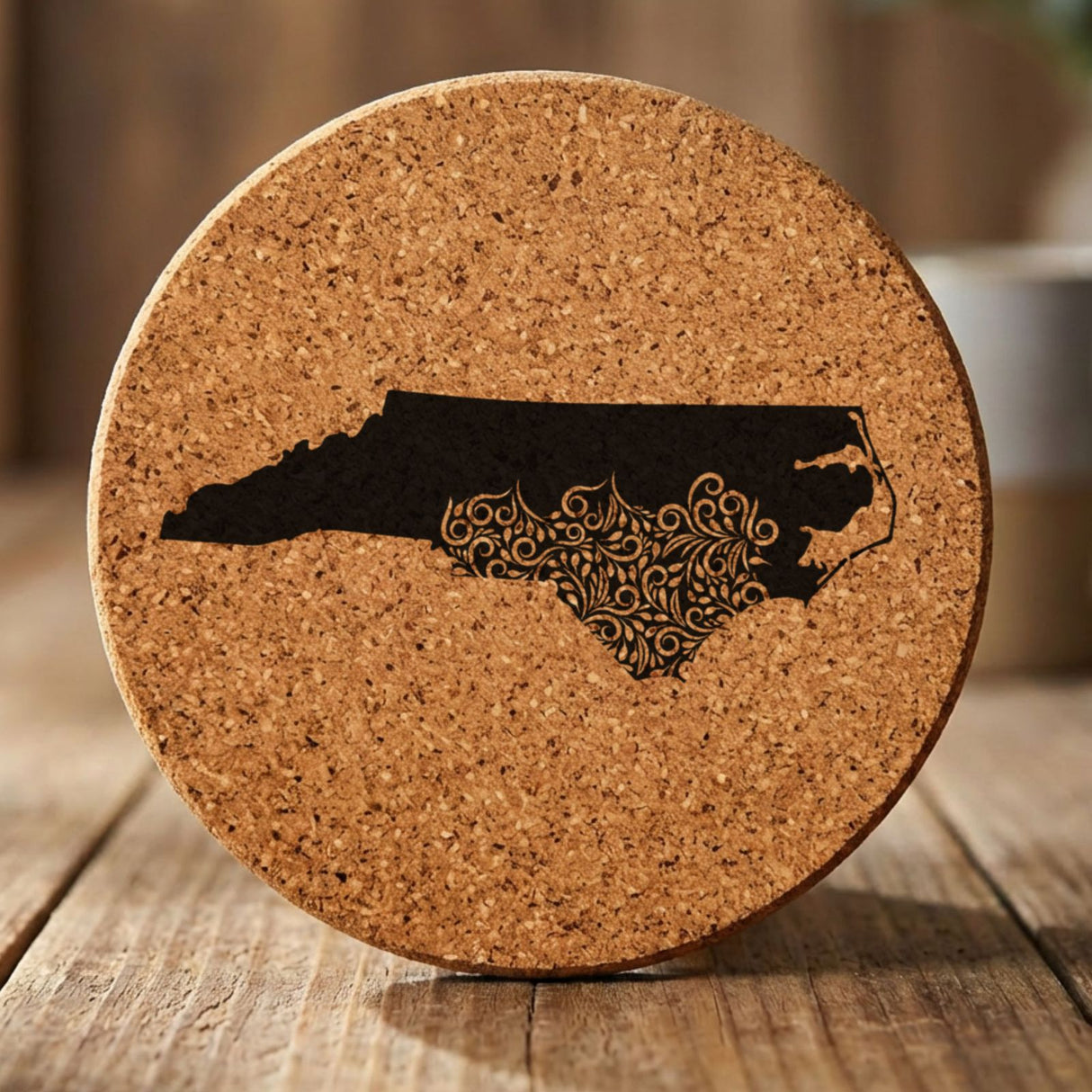 North Carolina round cork coaster engraved with the state shape in ornate floral scrollwork
