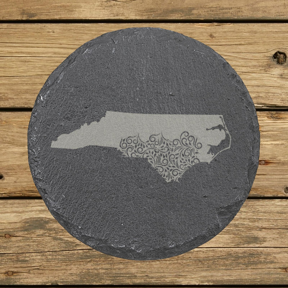 North Carolina round slate coaster engraved with the state shape in ornate floral scrollwork