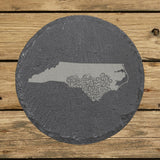 North Carolina round slate coaster engraved with the state shape in ornate floral scrollwork