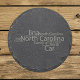 North Carolina round slate coaster engraved with a word cloud of repeating North Carolina text
