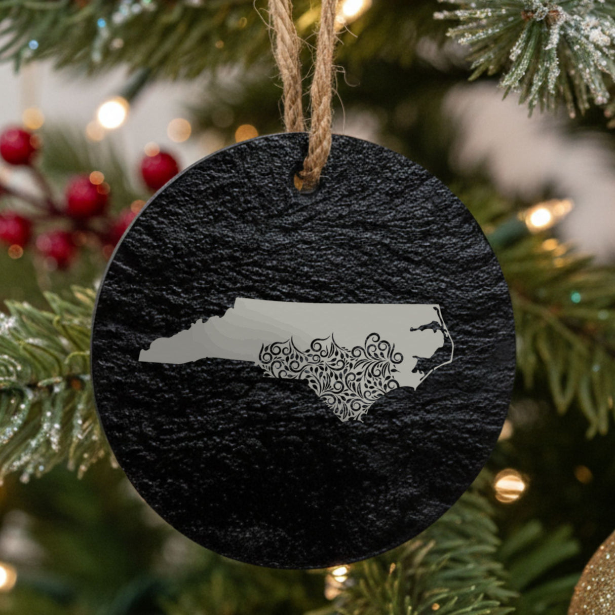 North Carolina round slate Christmas ornament engraved with the state shape in ornate floral scrollwork