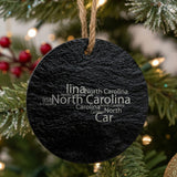 North Carolina round slate Christmas ornament engraved with a word cloud of repeating North Carolina text