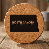 North Dakota round cork coaster engraved with the state shape and NORTH DAKOTA in bold lettering