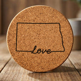 North Dakota round cork coaster engraved with a hand-drawn state outline and love in cursive