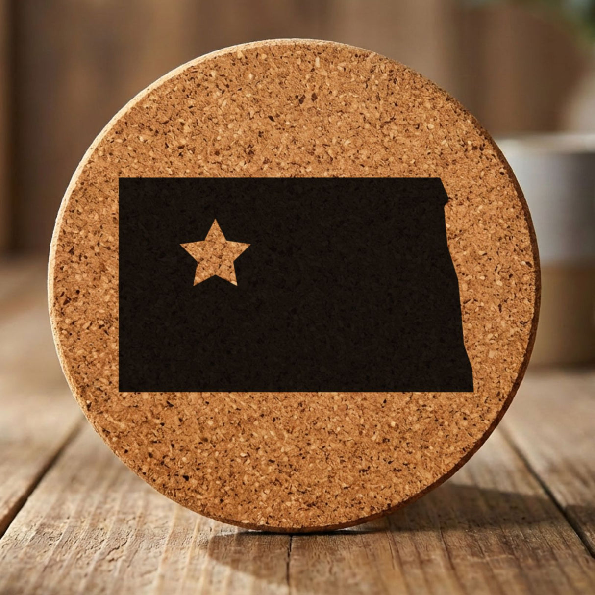 North Dakota round cork coaster engraved with the state shape and a star