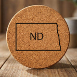 North Dakota round cork coaster engraved with the state outline and ND initials