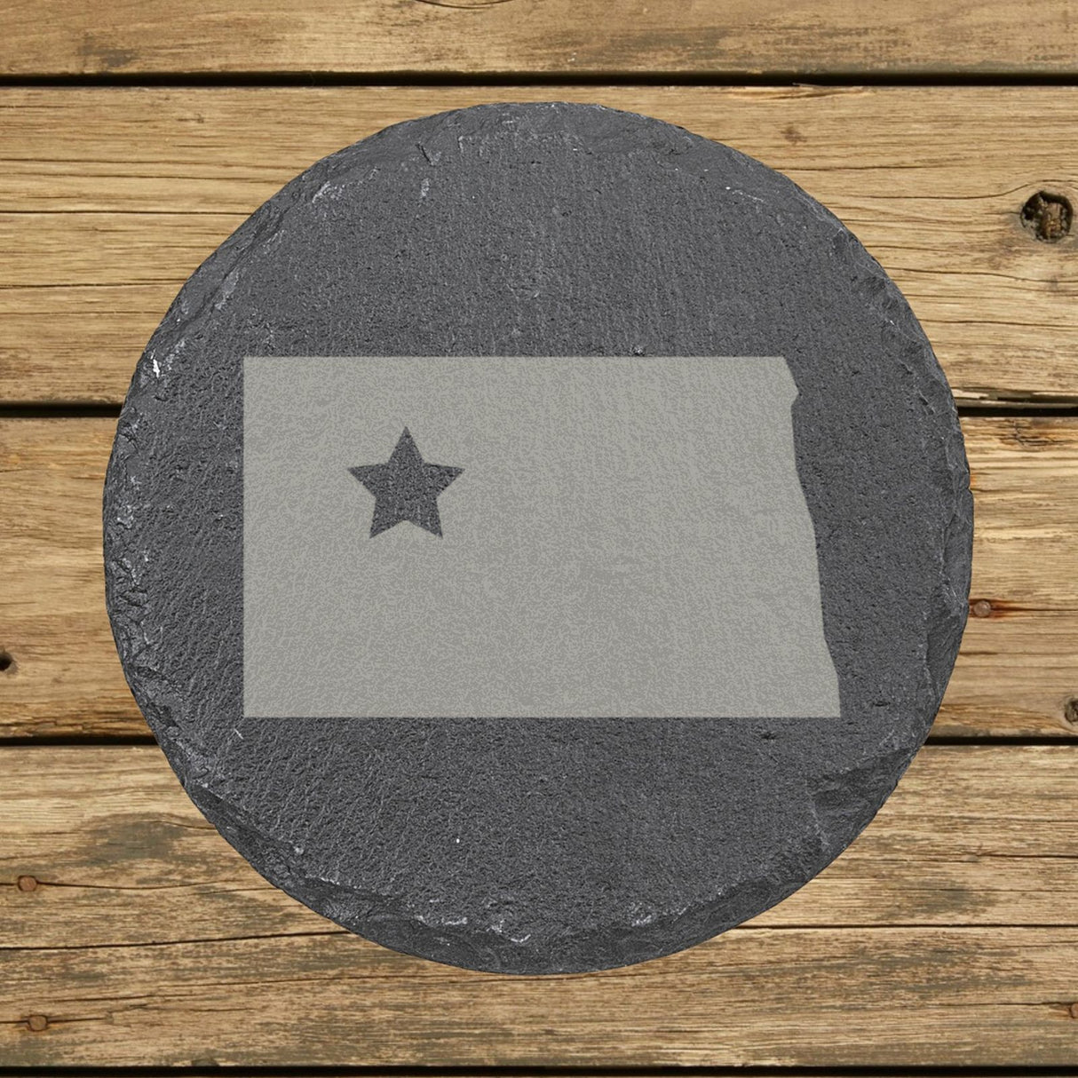 North Dakota round slate coaster engraved with the state shape and a star