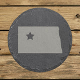 North Dakota round slate coaster engraved with the state shape and a star