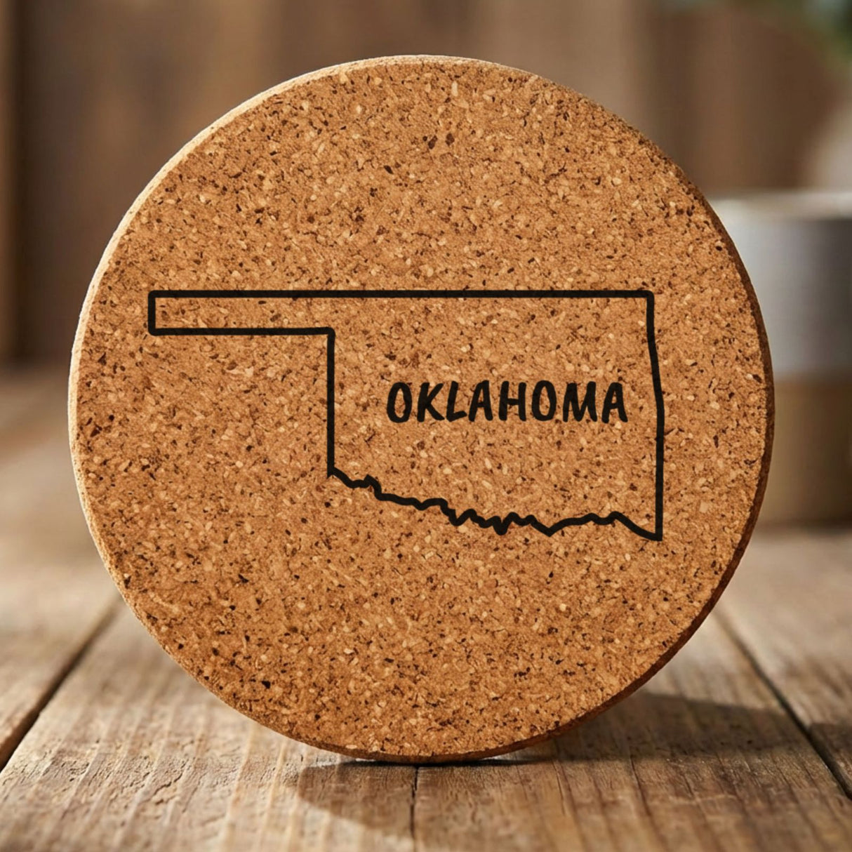 Oklahoma round cork coaster engraved with the state outline and OKLAHOMA in hand-drawn brush lettering