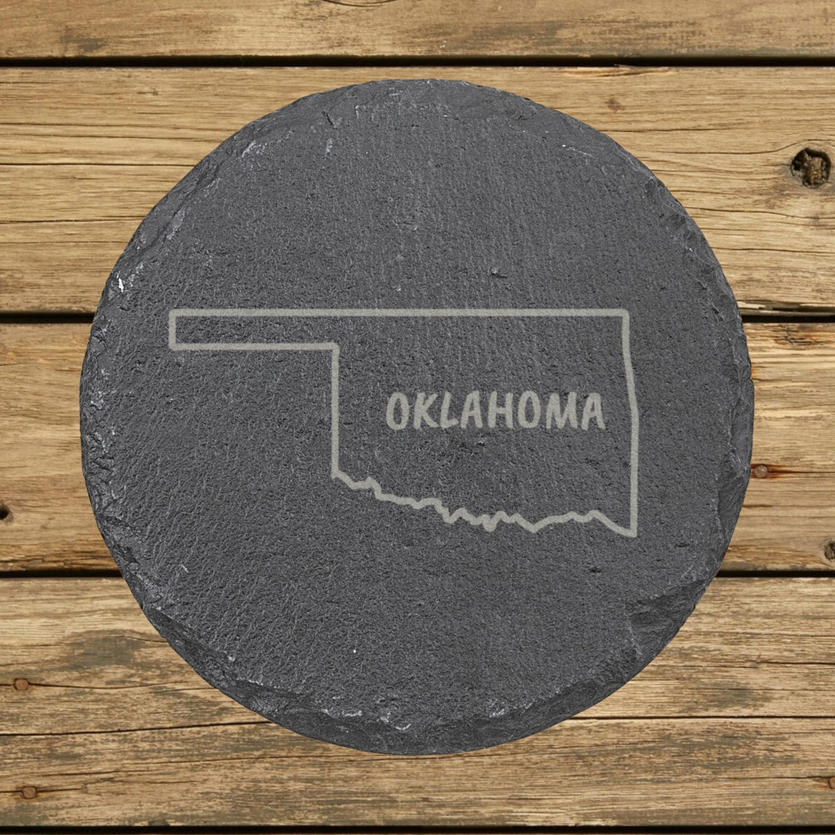 Oklahoma round slate coaster engraved with the state outline and OKLAHOMA in hand-drawn brush lettering