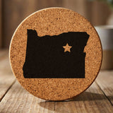 Oregon round cork coaster engraved with the state shape and a star