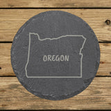 Oregon round slate coaster engraved with the state outline and OREGON in hand-drawn brush lettering